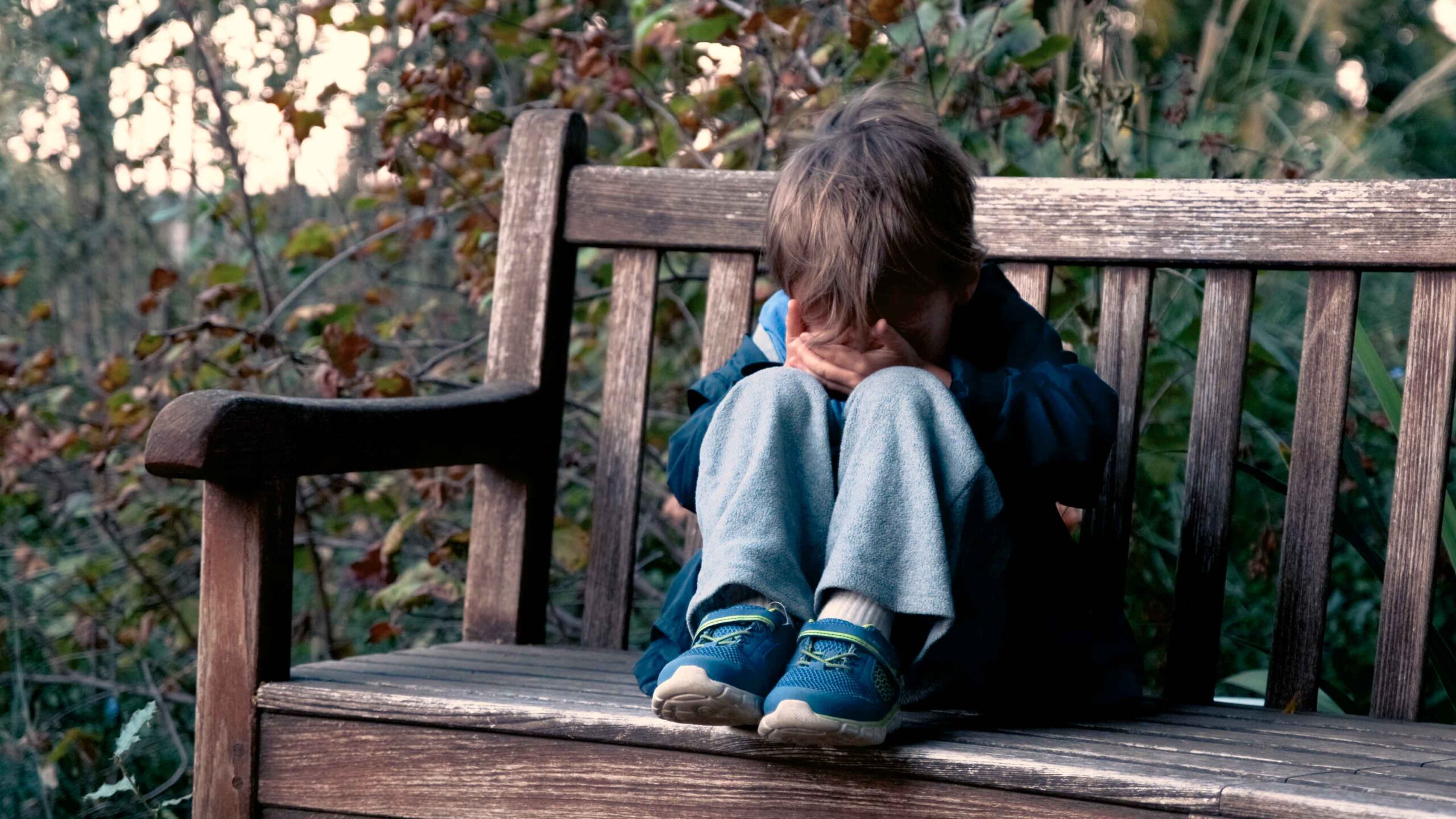 Image of a child crying on a park bench
