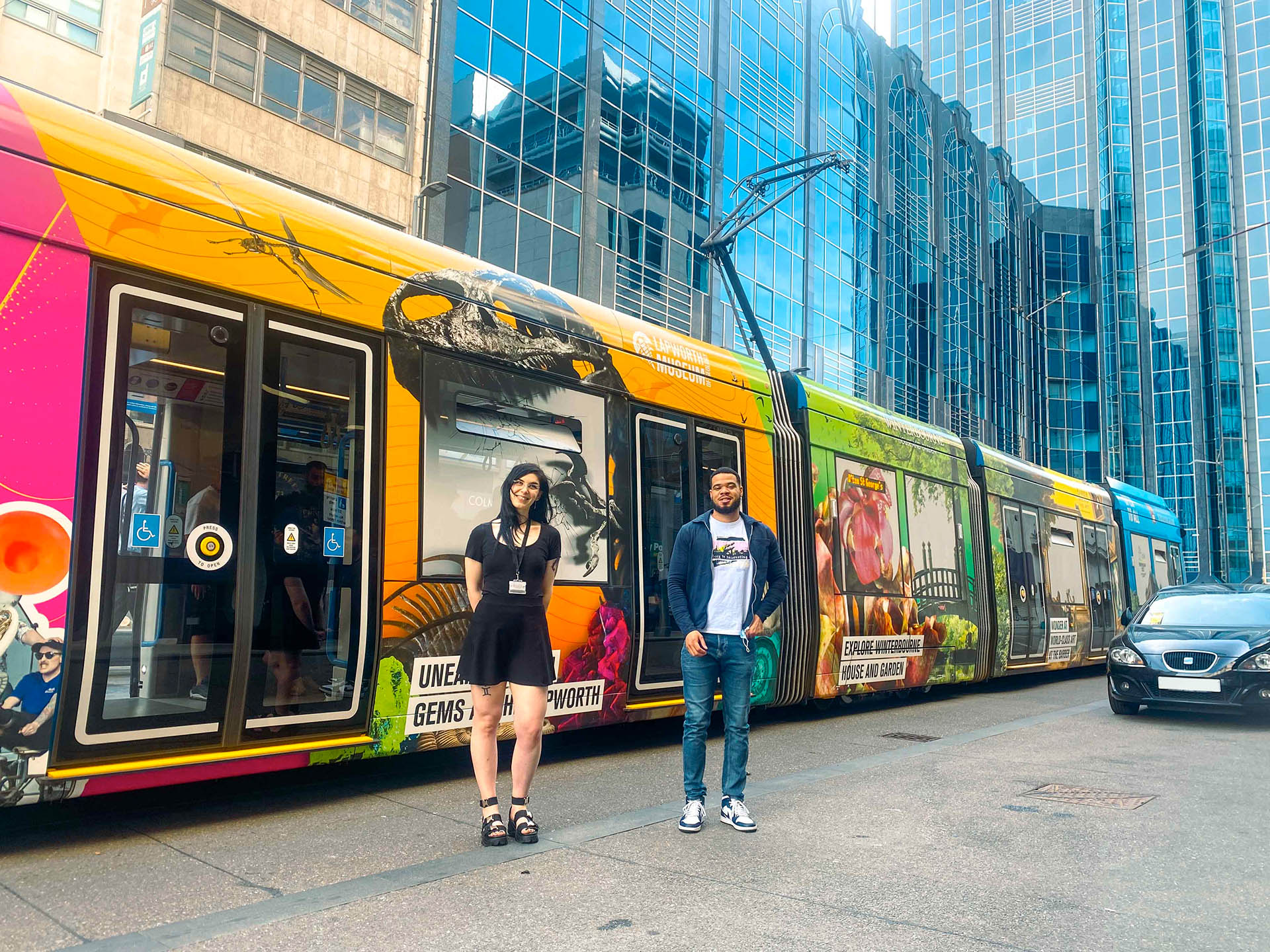 Designers Adriana (left) and Armani (right) in front of the tram wrap they designed during the 2022 Birmingham Commonwealth Games to promote the cultural attractions of the University of Birmingham.